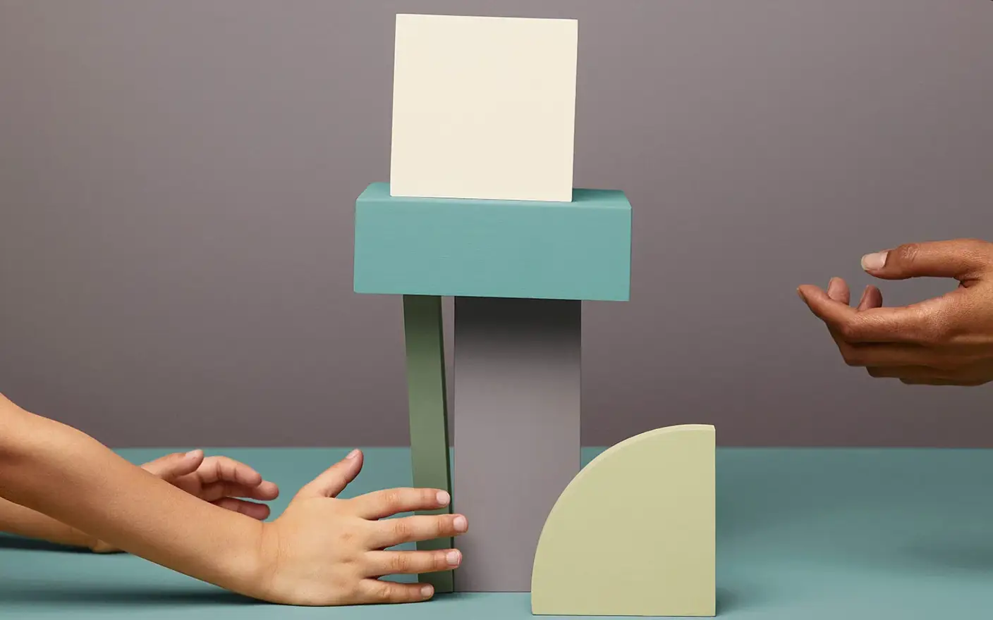 Two pairs of hands playing with painted elements, stocking them on top of each other.